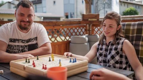 Eine pädagogische Fachkraft spielt zusammen mit Jugendlichen 'Mensch-Ärger-dich-nicht'