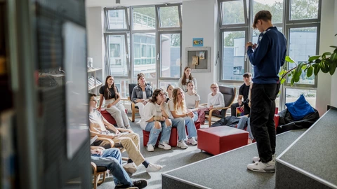 Ein Jugendlicher präsentiert einer interessierten Gruppe von Jugendlichen einen Vortrag